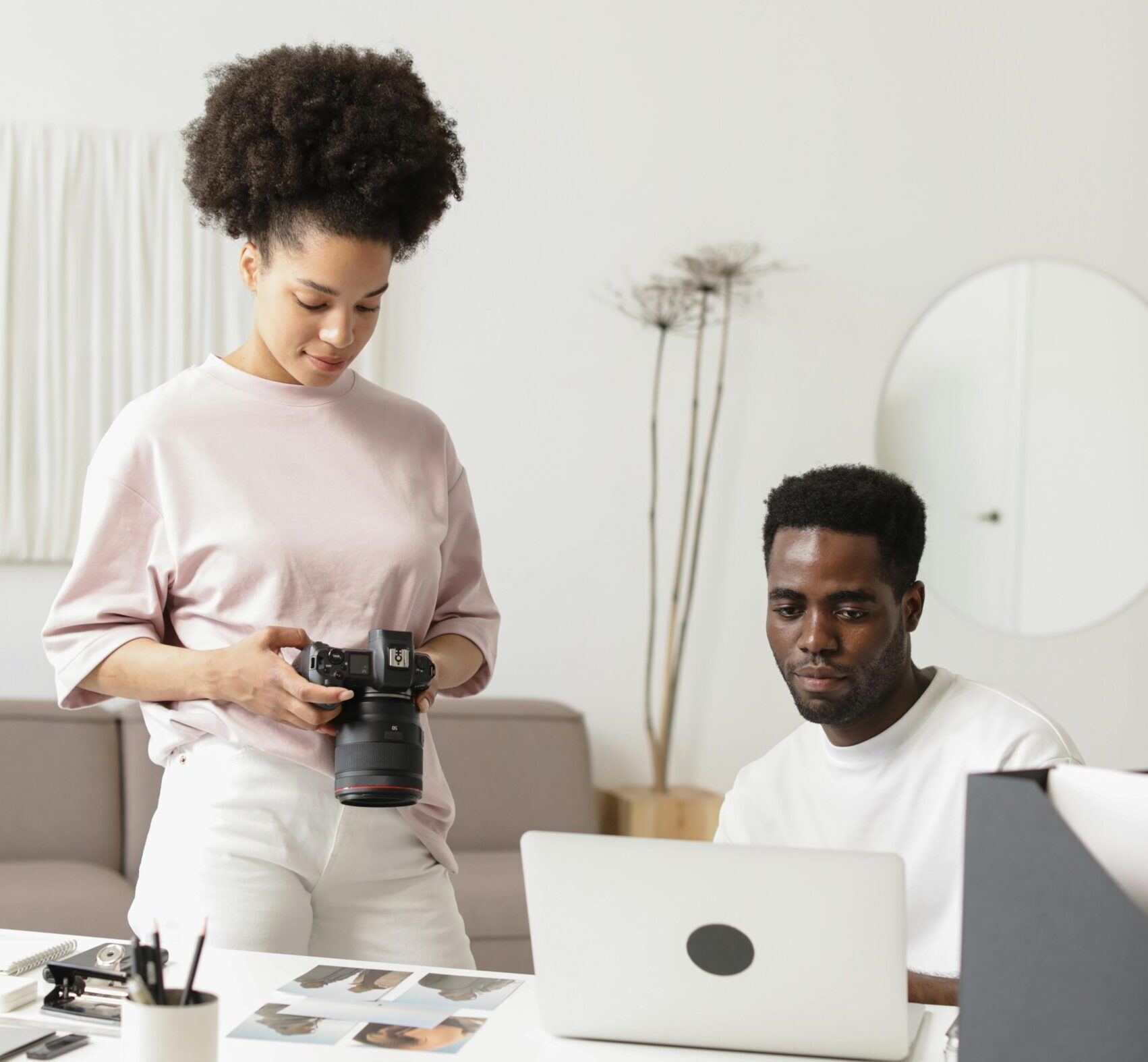 a woman holding a camera to a man looking at a laptop